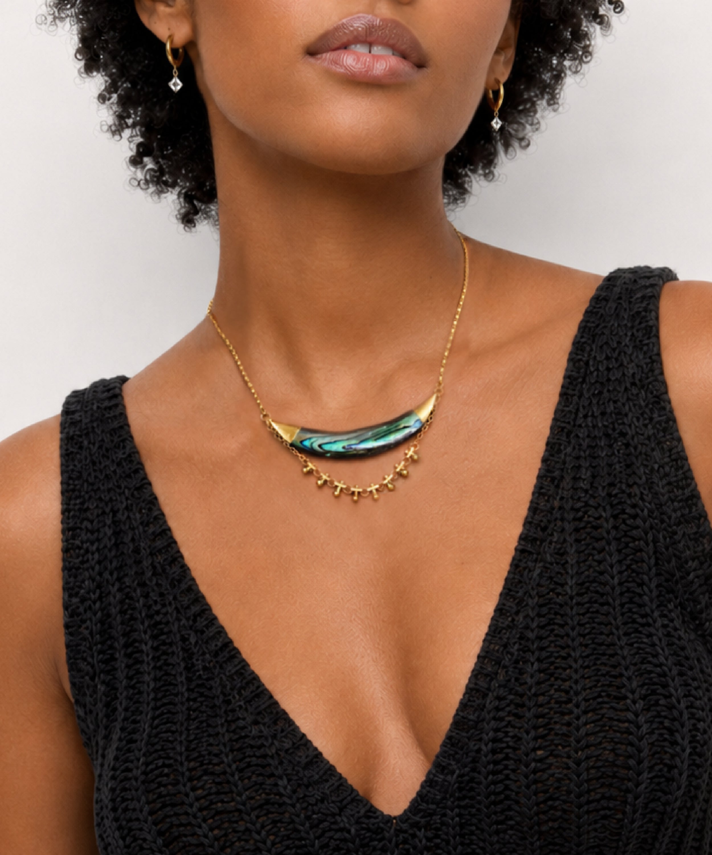 Woman wearing the Darya Abalone Crescent Necklace with a greens and blues and purple across the abalone, handcrafted by Alysian.