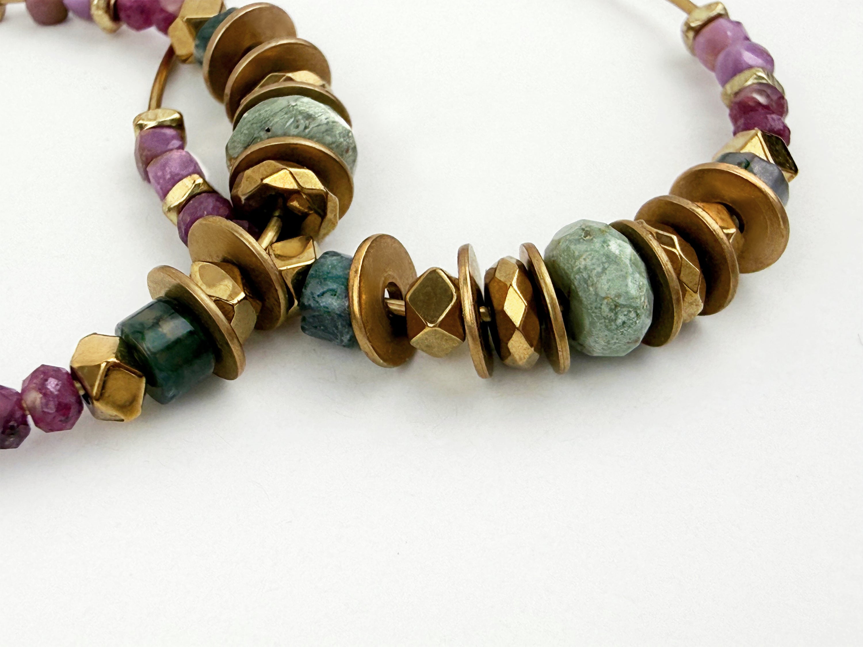A closely cropped detailed photo of the colorful Alysian Mirelle Multistone Hoop Earrings showing gemstones and brass accents.