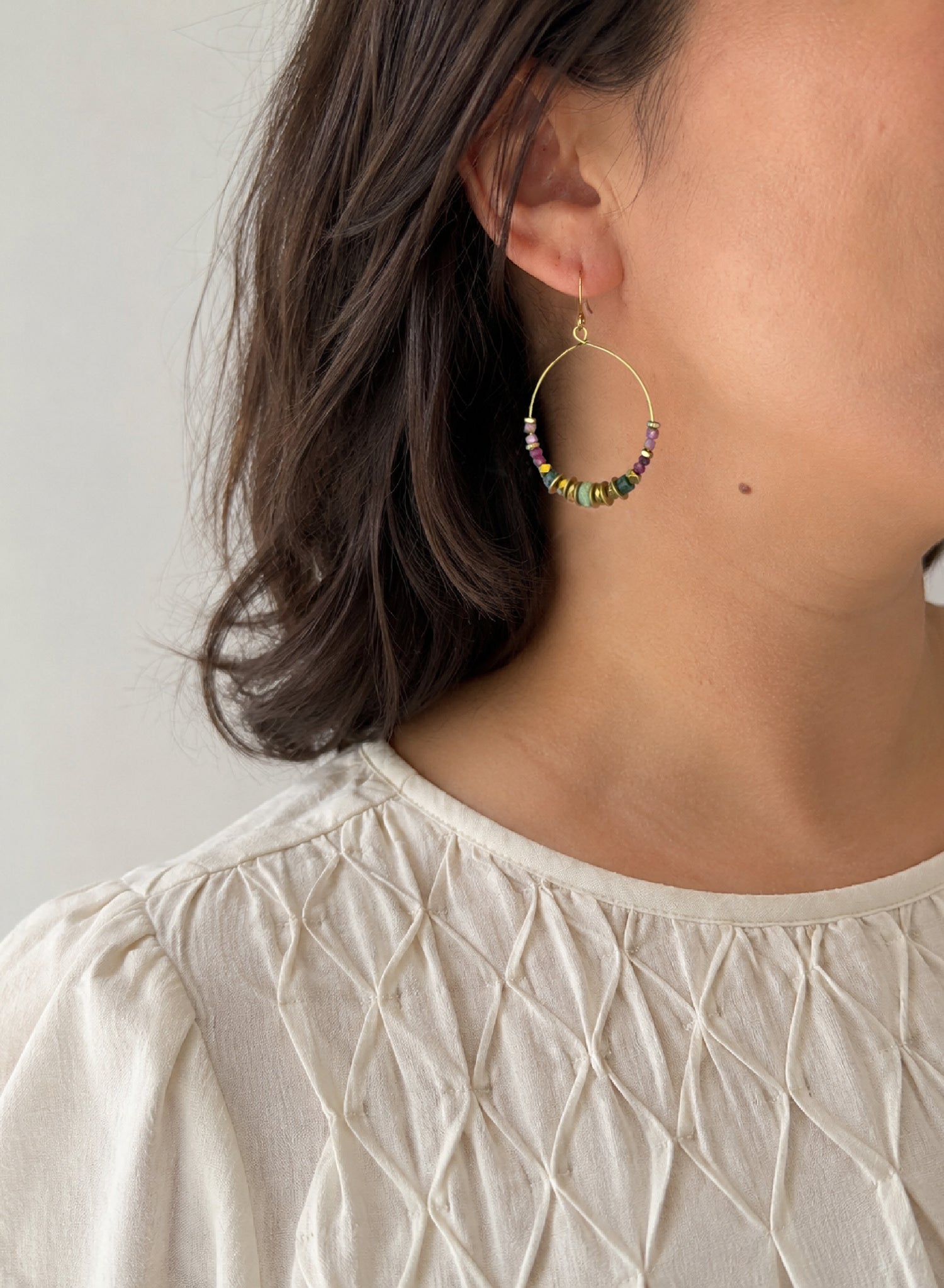 Close-up of a woman wearing the colorful gemstone beaded Mirelle Multistone Hoop Earring handcrafted by Alysian.
