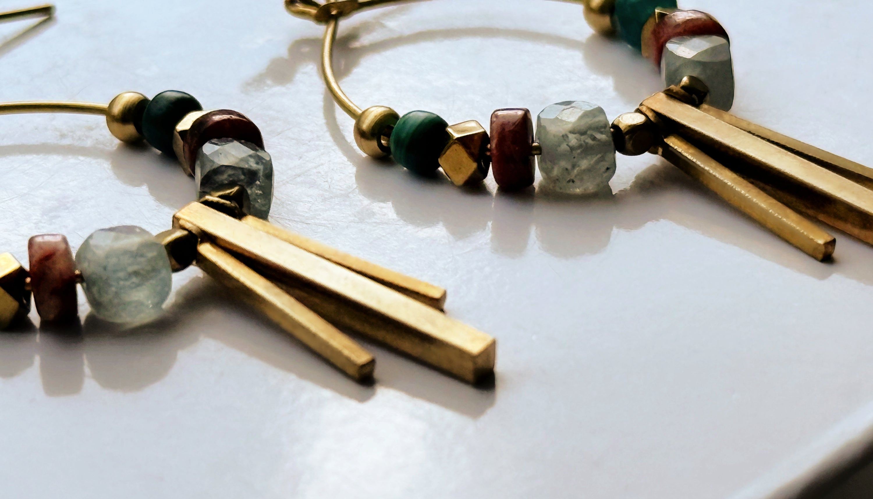 Close-up of a Soren Apatite Hoops, showing the details of gemstone beads and brass design elements.