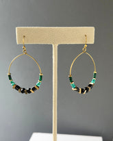Brass hoop earrings with green malachite, turquoise stones, black beads and edgy brass acccents on an earring stand — Adira hoop by Alysian.
