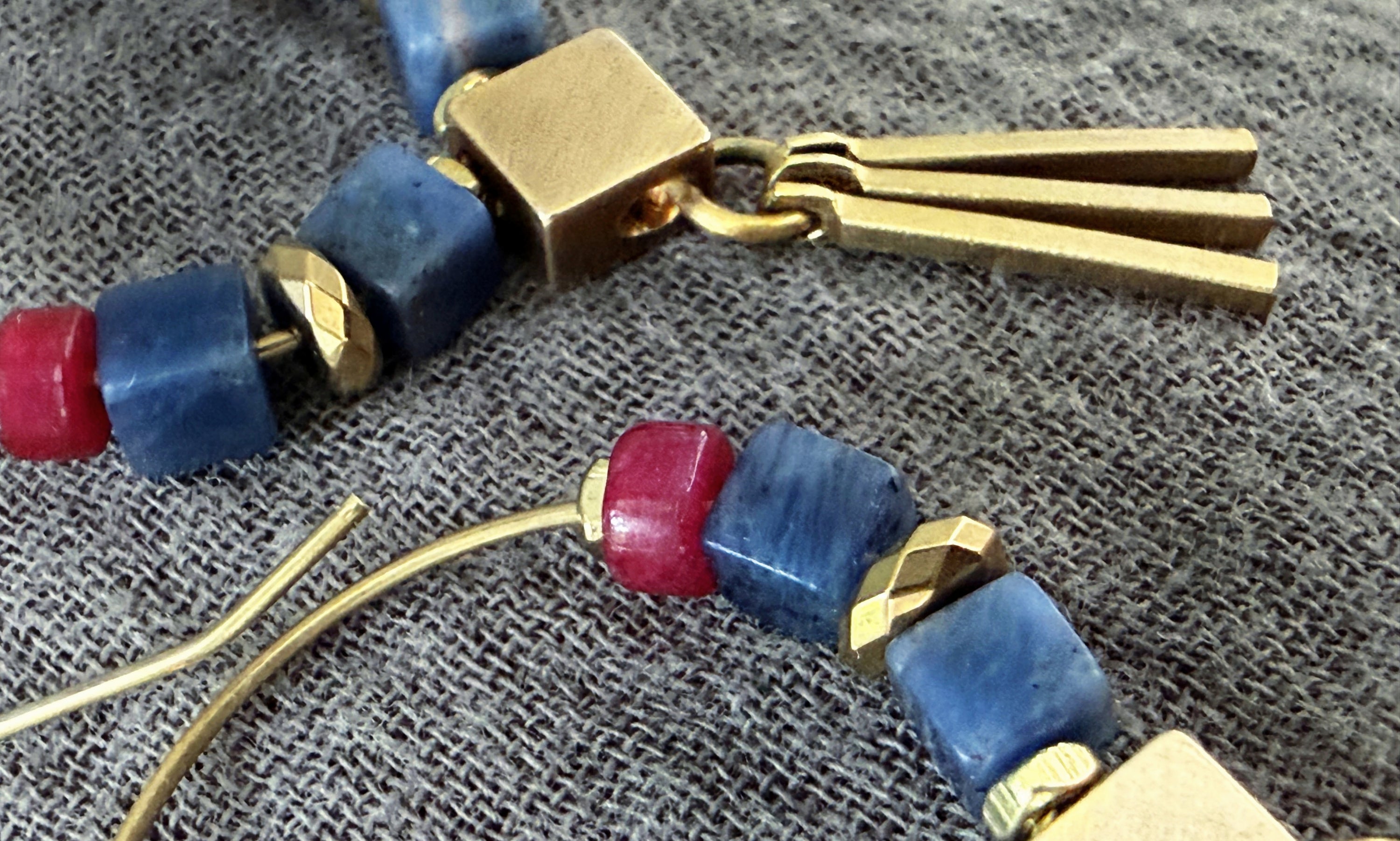 Close up of the Azra Sodalite Hoop Earring, showing smooth blue gemstones and sleek metal fringe. 