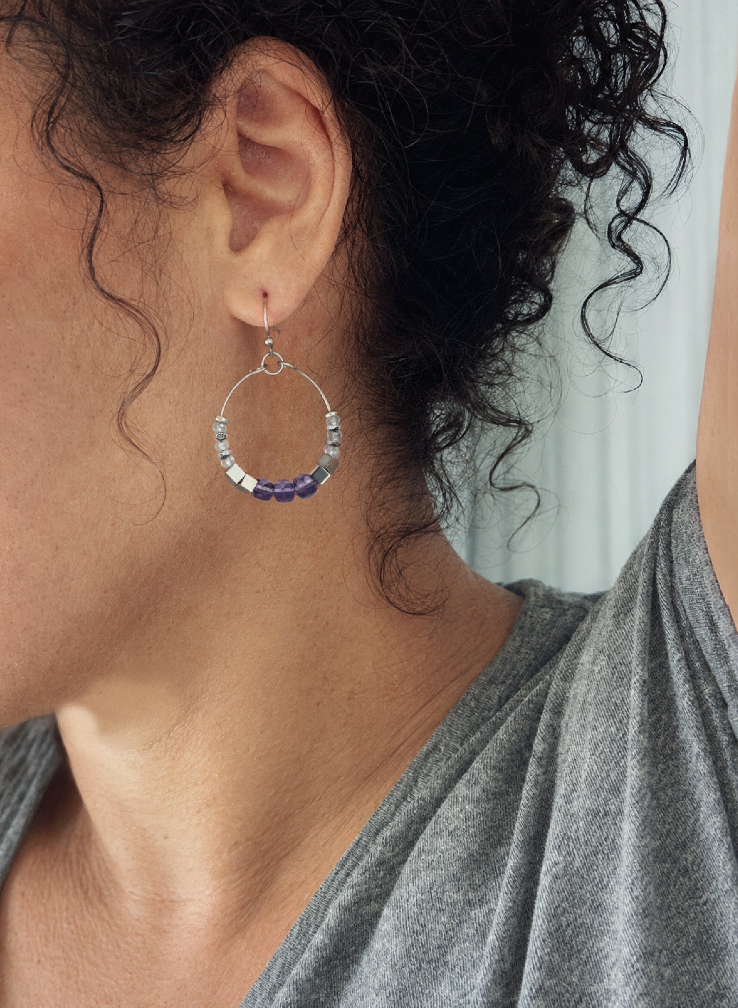 Close-up of a woman wearing Luma Amethyst Hoop earrings by Alysian.