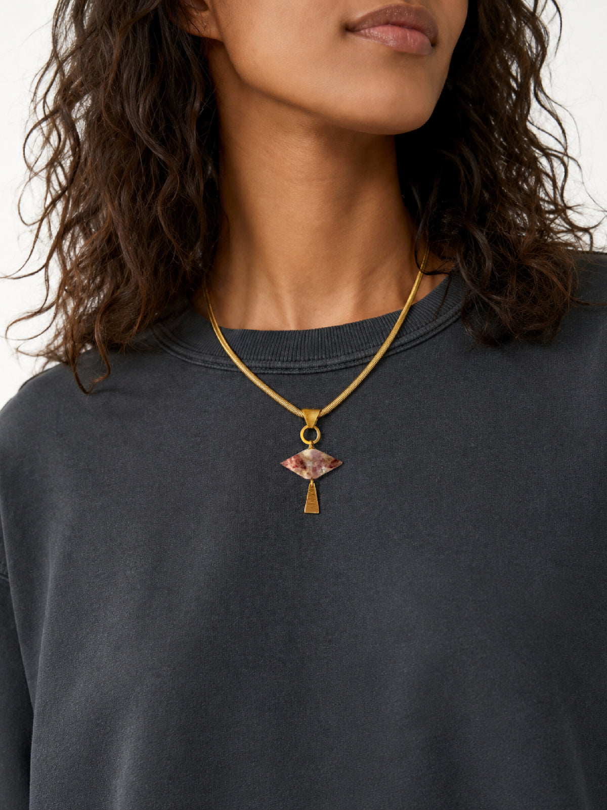 A close-up of a model wearing a brass flat snake chain necklace with a geometric gemstone pendant and vintage details, handcrafted by Alysian. 
