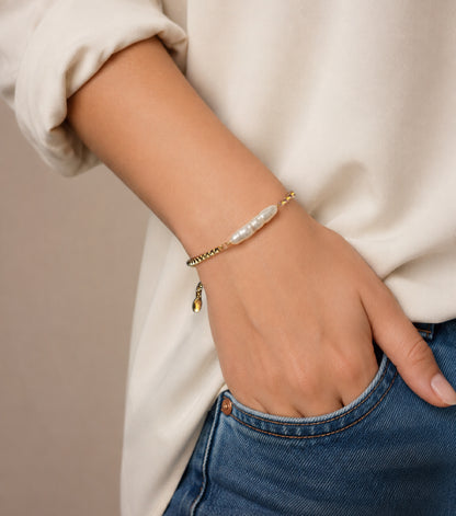 A close-up of the Padma adjustable gold chain bracelet with a white biwa pearl bead in the center, handcrafted by Alysian.