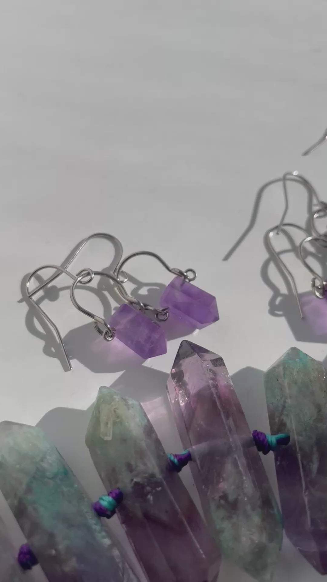 Multiple pairs of hypoallergenic Amrita Amethyst earrings of stainless steel, shining in natural light - handcrafted by Alysian.