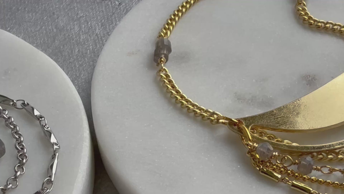 Gold Lusine adjustable crescent pendant necklace with draped chains and stones, one silver and one gold, on a luxe, close up, handcrafted by Alysian.
