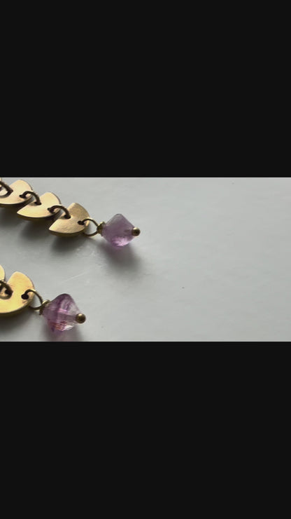 A video panning across three pairs of brass linear Alune Earrings, each pair featuring different stones: purple fluorite, blue sodalite and green fluorite drops. Handcrafted by Alysian.